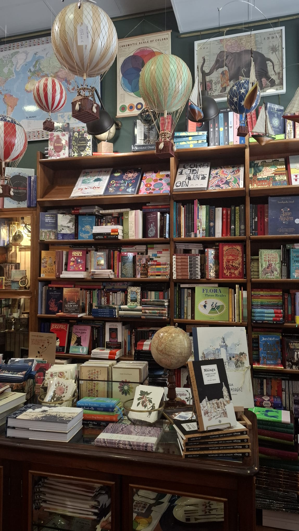Bücherregale mit Weltkarten, Heißluftballon-Modellen und Reisebüchern bei Mapas y Compañía in Málaga.